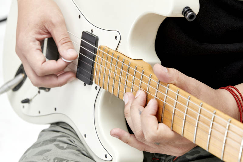 示范演奏摇滚电吉他的亚洲男性乐手人像局部特写图片