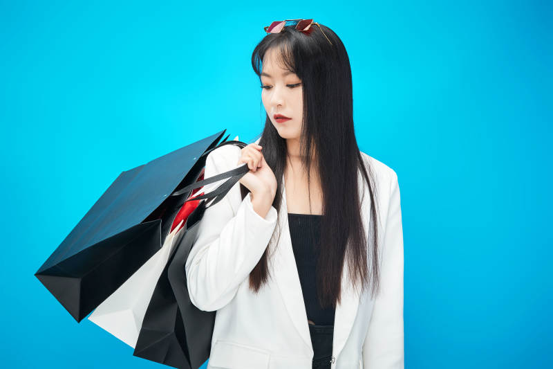 青蓝色背景下手提购物袋的亚洲时尚少女图片