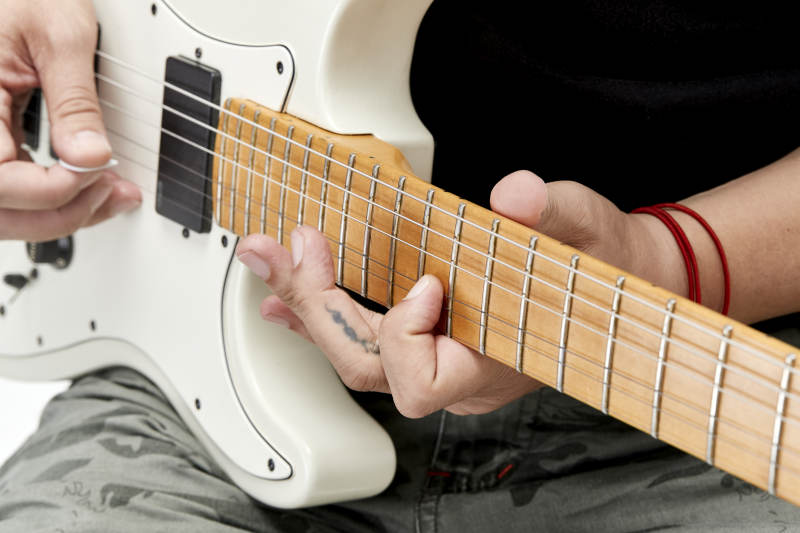 示范演奏摇滚电吉他的亚洲男性乐手人像局部特写图片