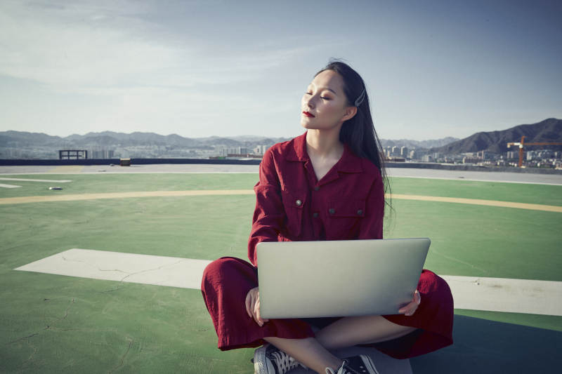 亚洲商务年轻女性在楼顶停机坪使用电脑办公图片