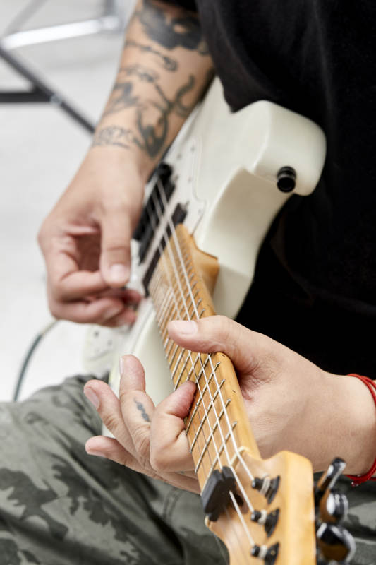 示范演奏摇滚电吉他的亚洲男性乐手人像局部特写图片