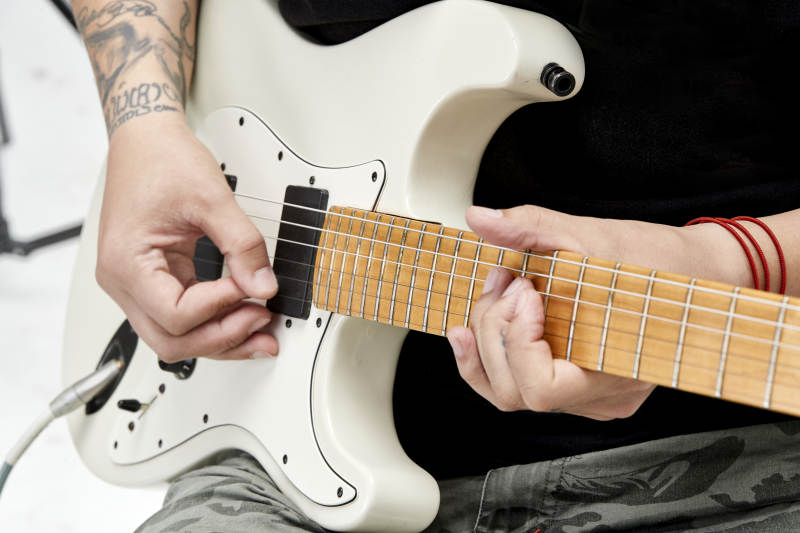 示范演奏摇滚电吉他的亚洲男性乐手人像局部特写图片