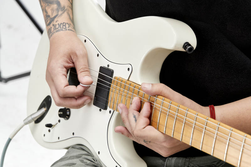 示范演奏摇滚电吉他的亚洲男性乐手人像局部特写图片