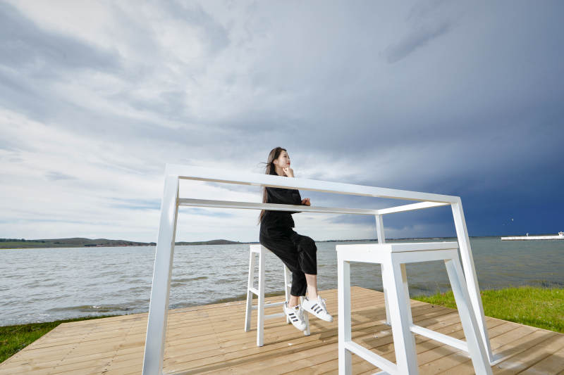 悠闲的坐在美丽湖岸码头的长发少女图片