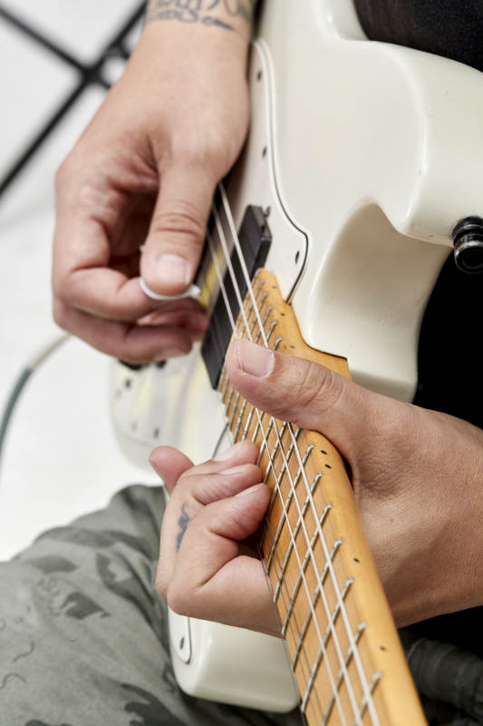 示范演奏摇滚电吉他的亚洲男性乐手人像局部特写图片