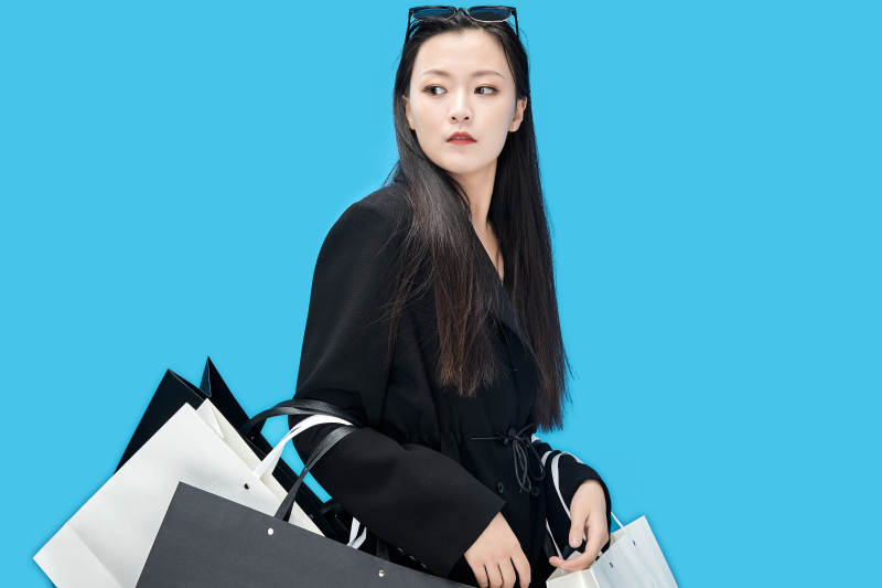 青蓝色背景下手提购物袋的亚洲时尚少女图片