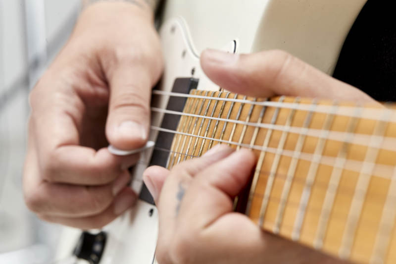 示范演奏摇滚电吉他的亚洲男性乐手人像局部特写图片