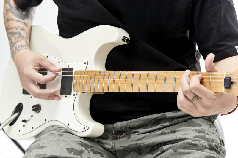 示范演奏摇滚电吉他的亚洲男性乐手人像局部特写图片