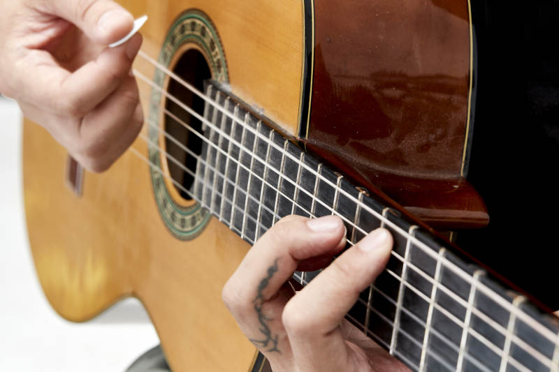 示范演奏古典吉他的亚洲男性乐手人像局部特写图片