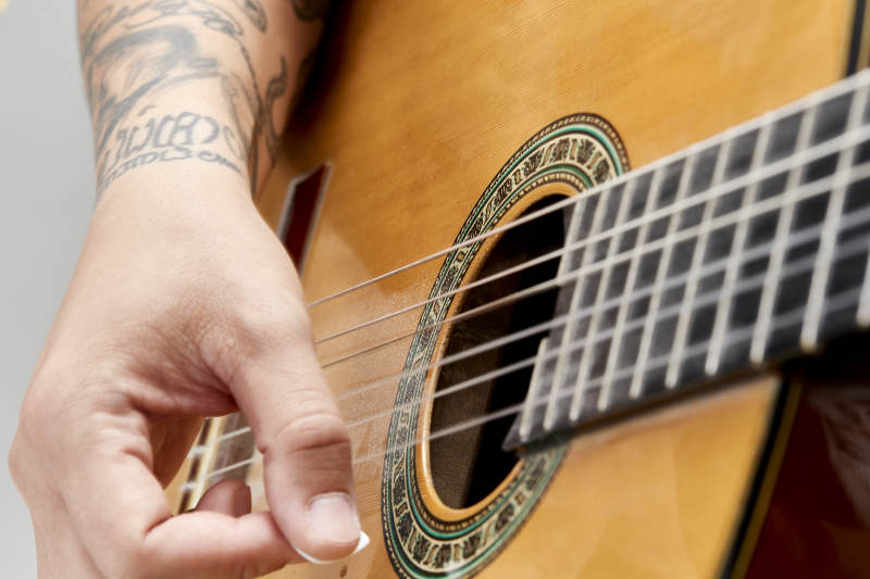 示范演奏古典吉他的亚洲男性乐手人像局部特写图片