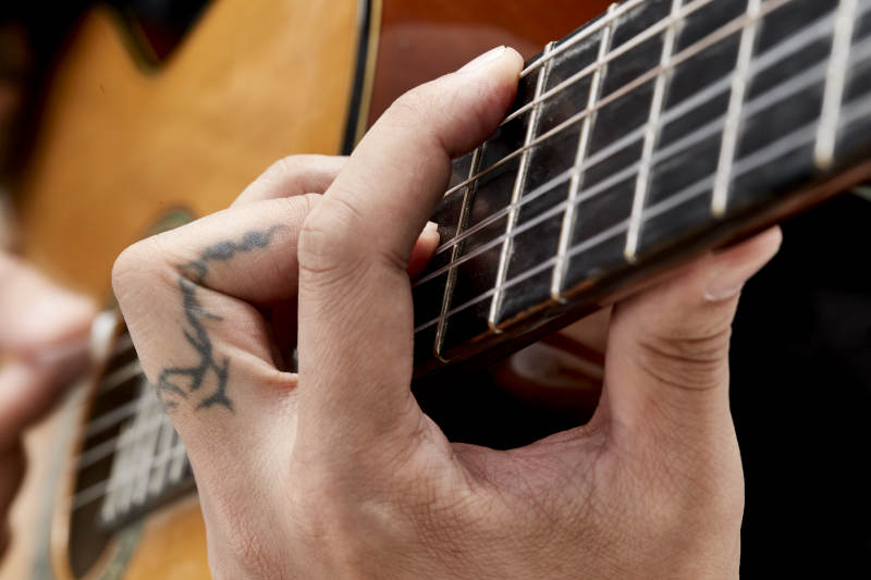 示范演奏古典吉他的亚洲男性乐手人像局部特写图片