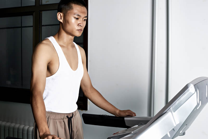 在室内用跑步机进行锻炼的亚洲健身男士形象图片