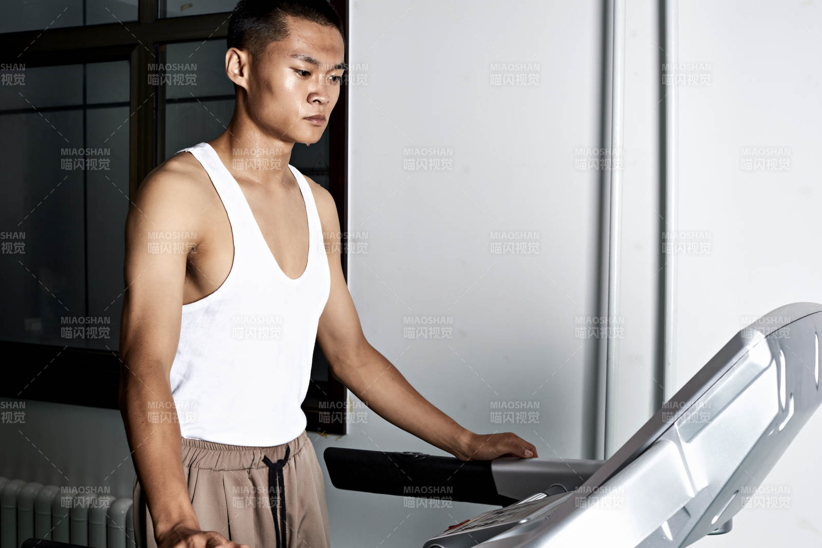 在室内用跑步机进行锻炼的亚洲健身男士形象图片