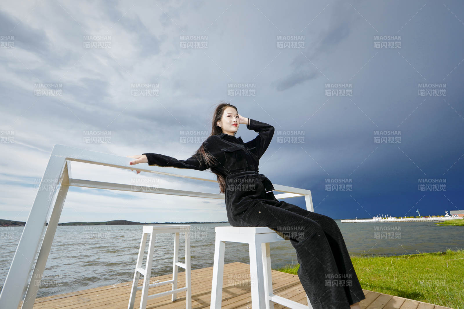 悠闲的坐在美丽湖岸码头的长发少女图片