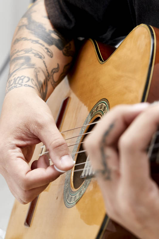 示范演奏古典吉他的亚洲男性乐手人像局部特写图片