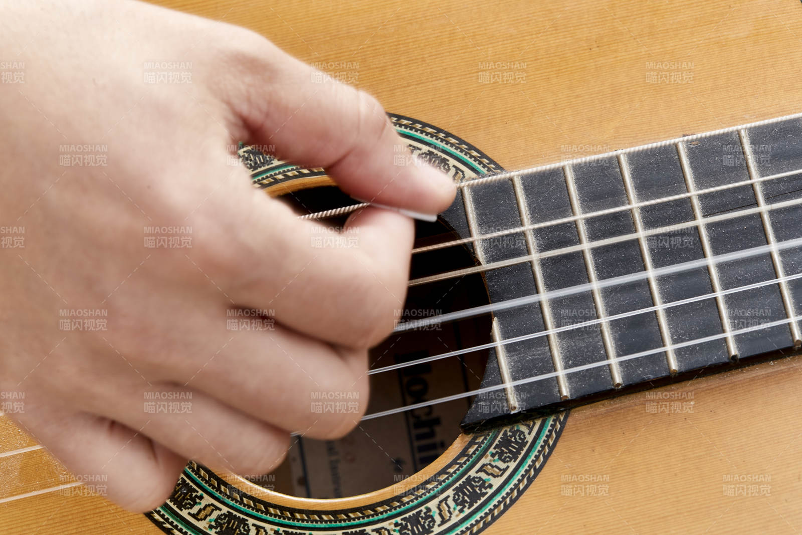 示范演奏古典吉他的亚洲男性乐手人像局部特写图片