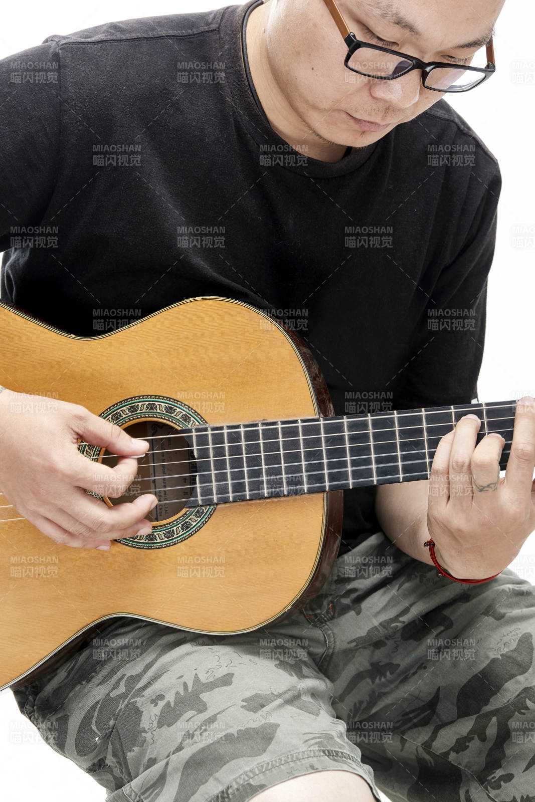 示范演奏古典吉他的亚洲男性乐手人像局部特写图片