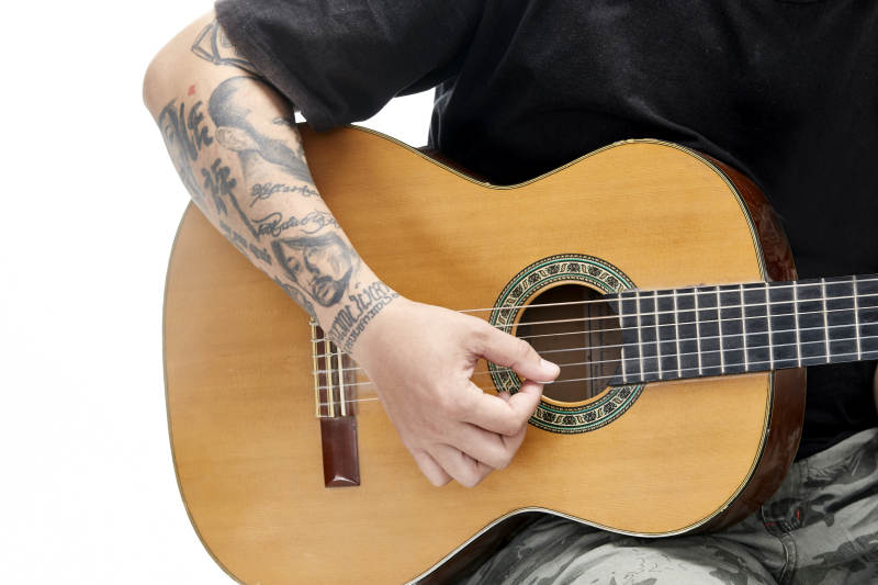 示范演奏古典吉他的亚洲男性乐手人像局部特写图片