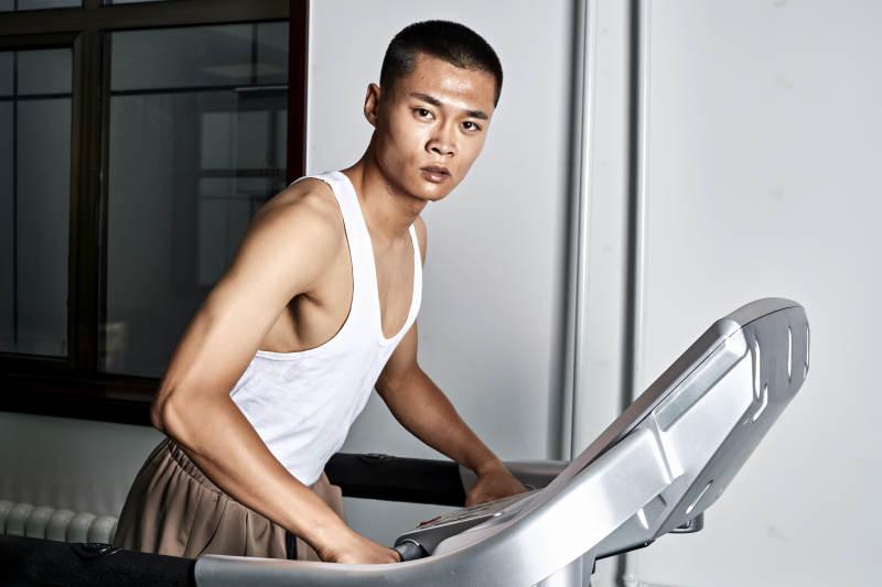 在室内用跑步机进行锻炼的亚洲健身男士形象图片