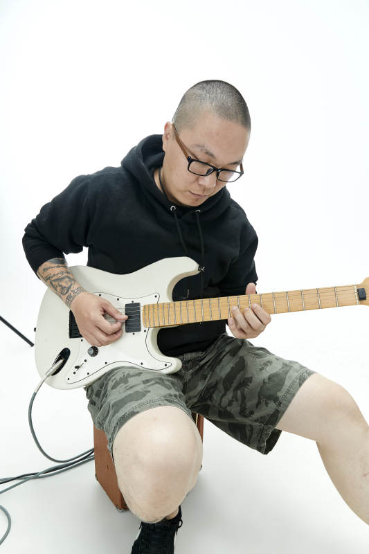 手持电吉他展示演奏的亚洲男性摇滚乐手人像图片