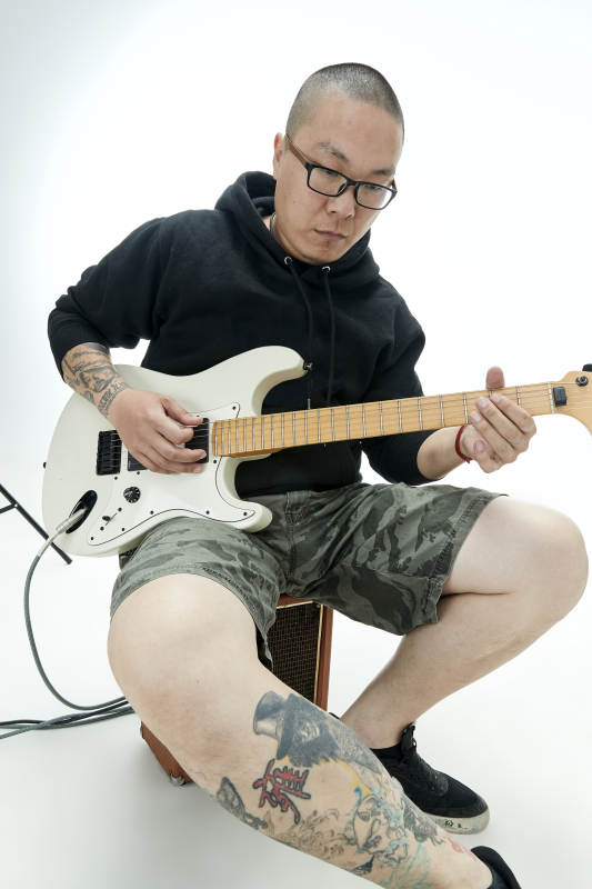 手持电吉他展示演奏的亚洲男性摇滚乐手人像图片