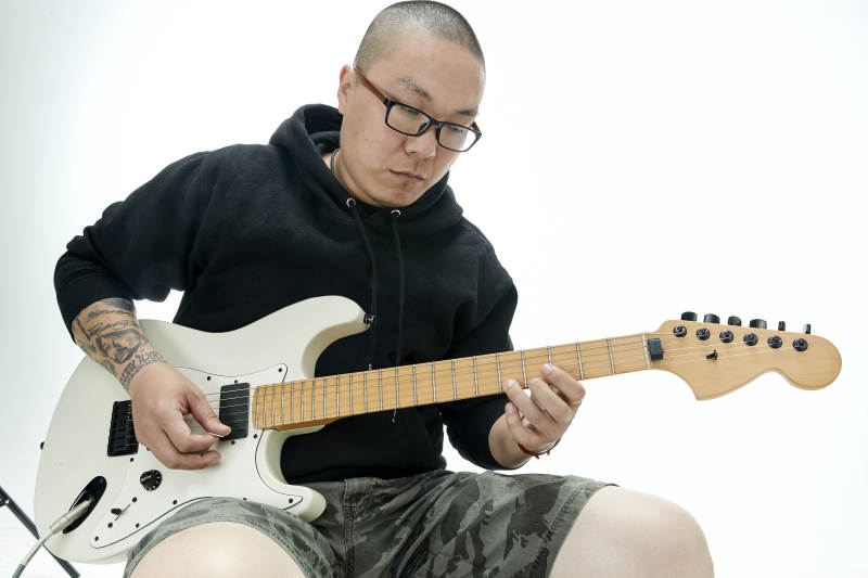 手持电吉他展示演奏的亚洲男性摇滚乐手人像图片