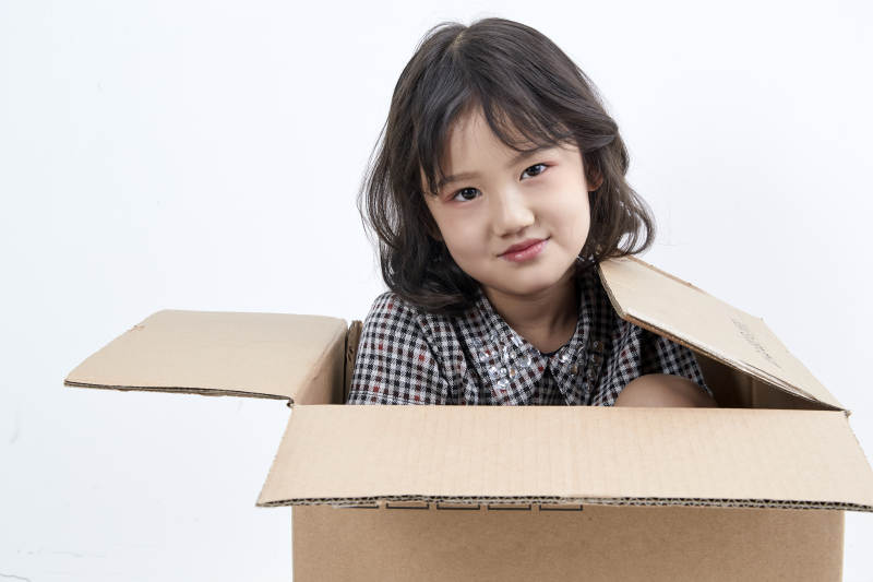 躲在纸箱中玩耍的调皮可爱亚洲小女孩儿童图片