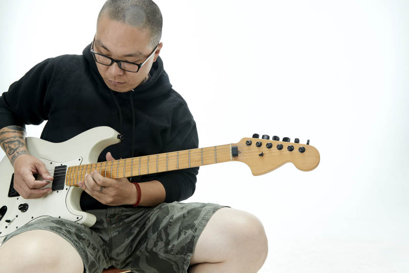 手持电吉他展示演奏的亚洲男性摇滚乐手人像图片