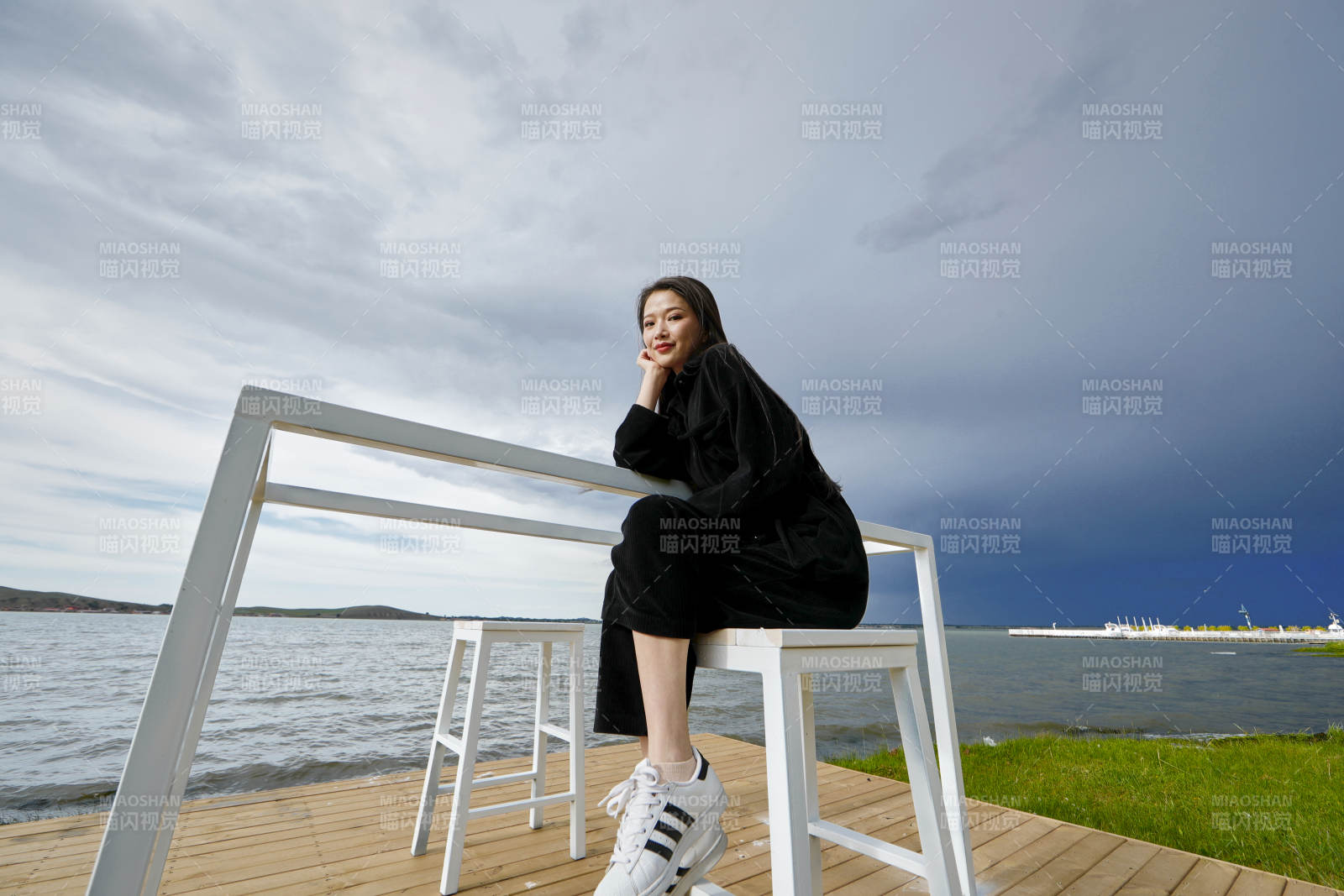 悠闲的坐在美丽湖岸码头的长发少女图片