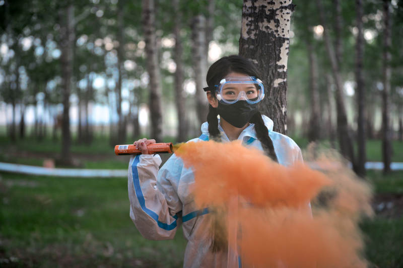 手执彩烟身穿防护服装的女性医疗人员图片