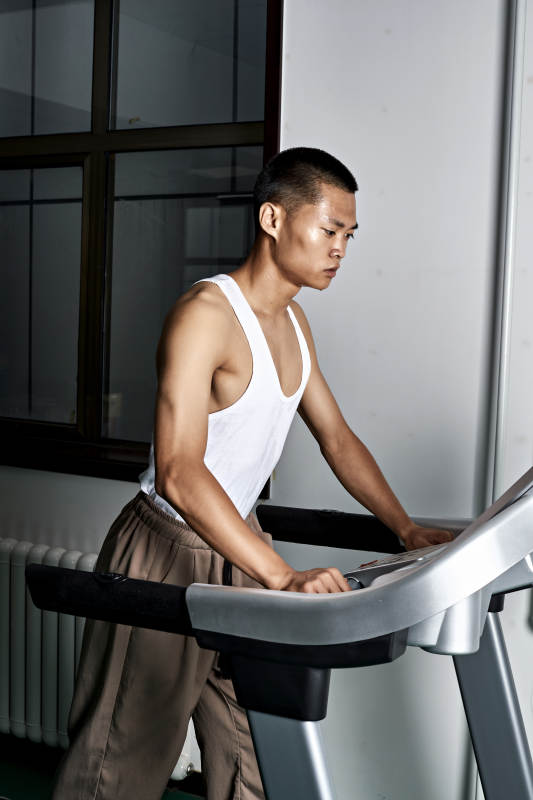 在室内用跑步机进行锻炼的亚洲健身男士形象图片