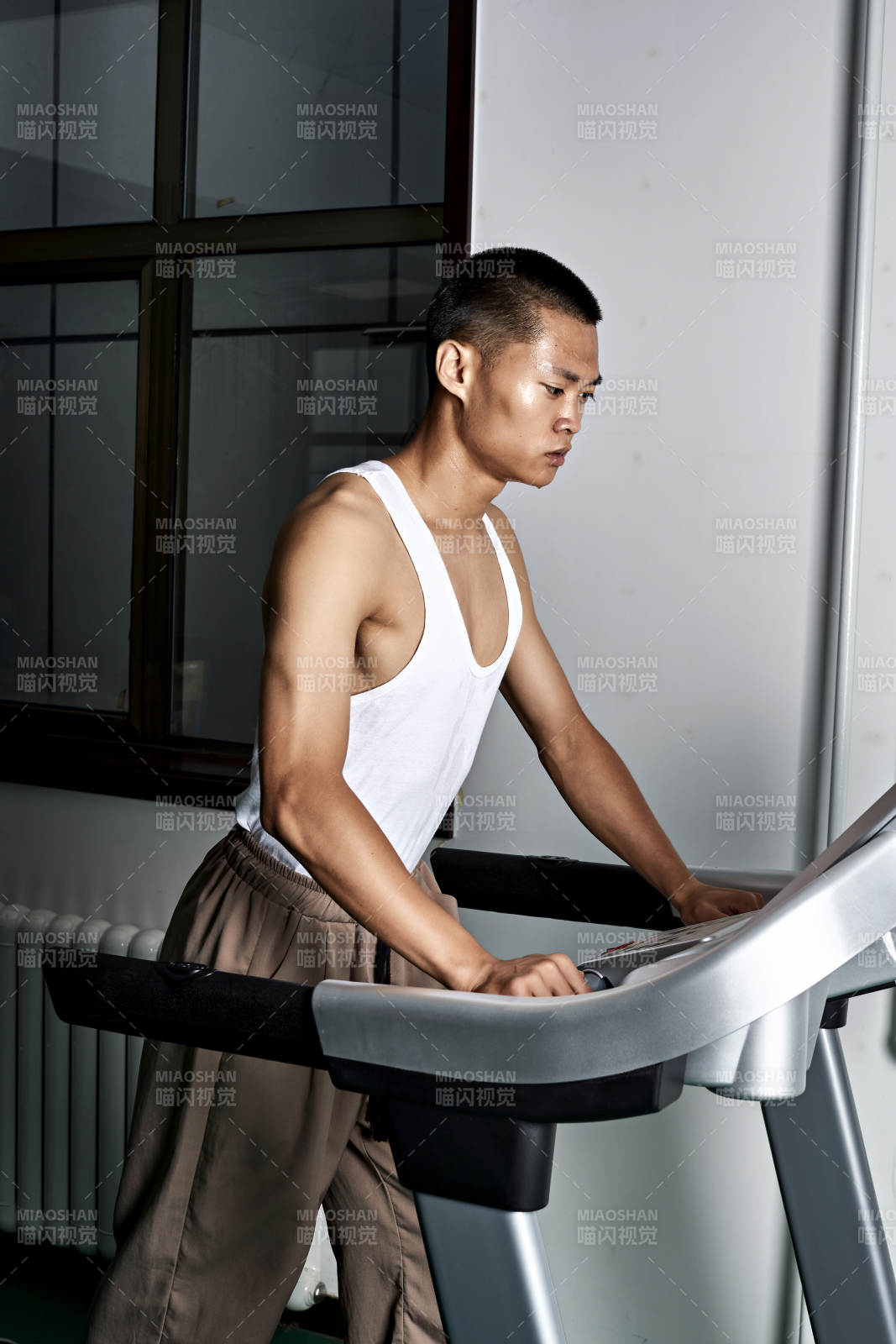 在室内用跑步机进行锻炼的亚洲健身男士形象图片