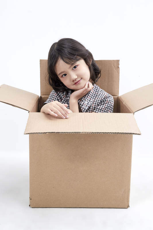 躲在纸箱中玩耍的调皮可爱亚洲小女孩儿童图片