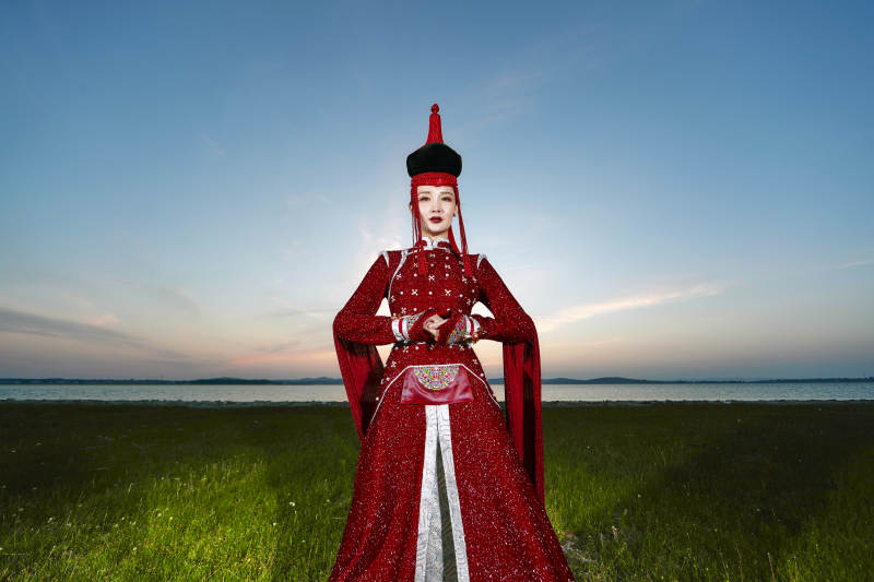 晚霞的草原湖畔穿蒙古族传统服饰的年轻女性图片