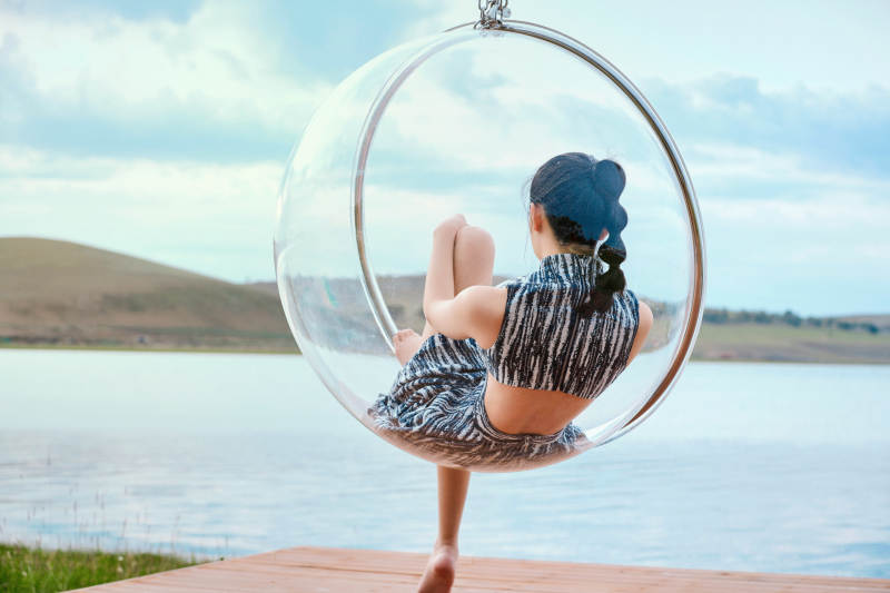 草原湖畔坐在透明秋千里的亚洲年轻女性人像图片