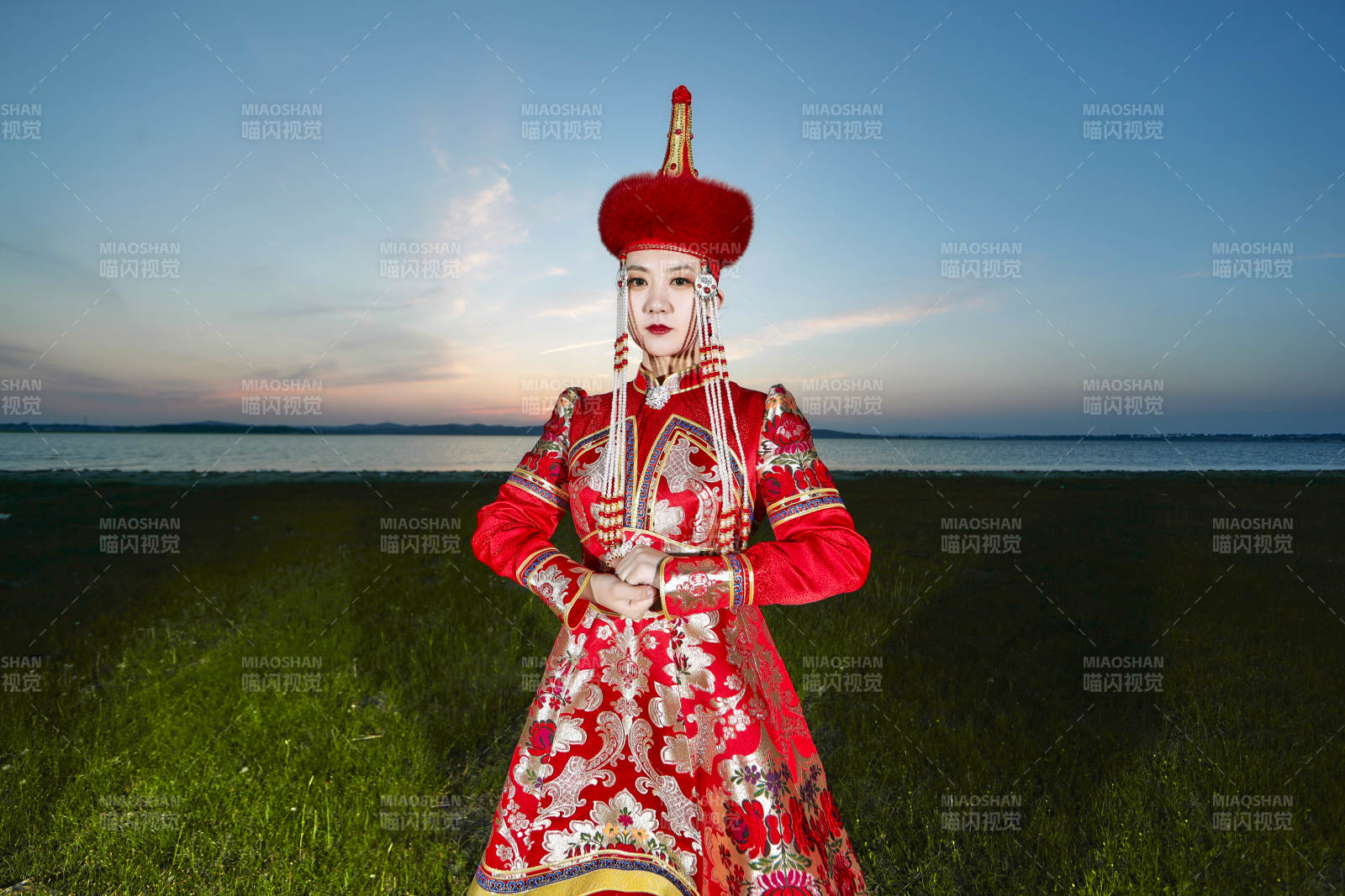 晚霞的草原湖畔穿蒙古族传统服饰的年轻女性图片