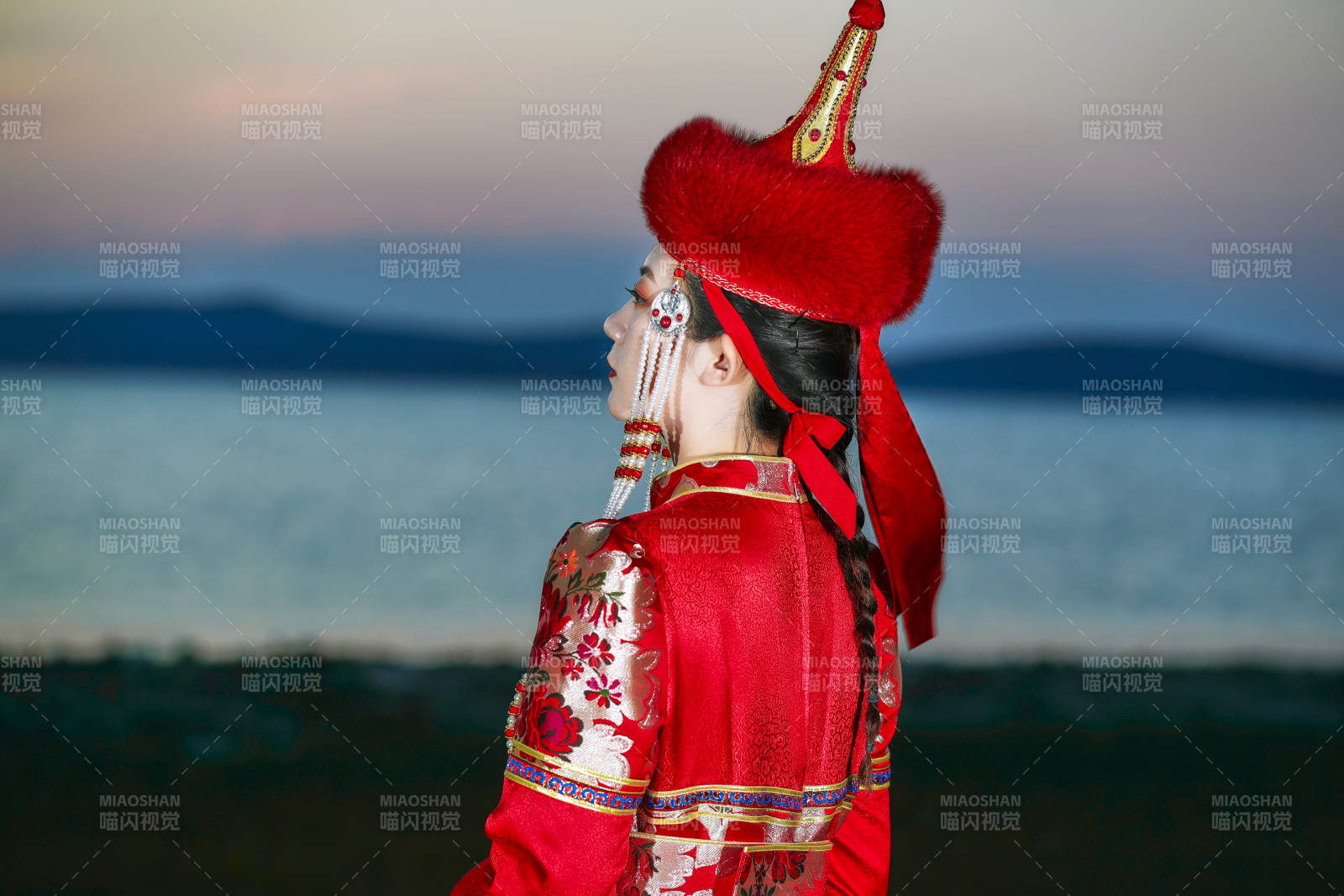 晚霞的草原湖畔穿蒙古族传统服饰的年轻女性图片