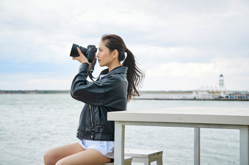 户外湖畔进行拍摄的亚洲青年女性摄影师图片