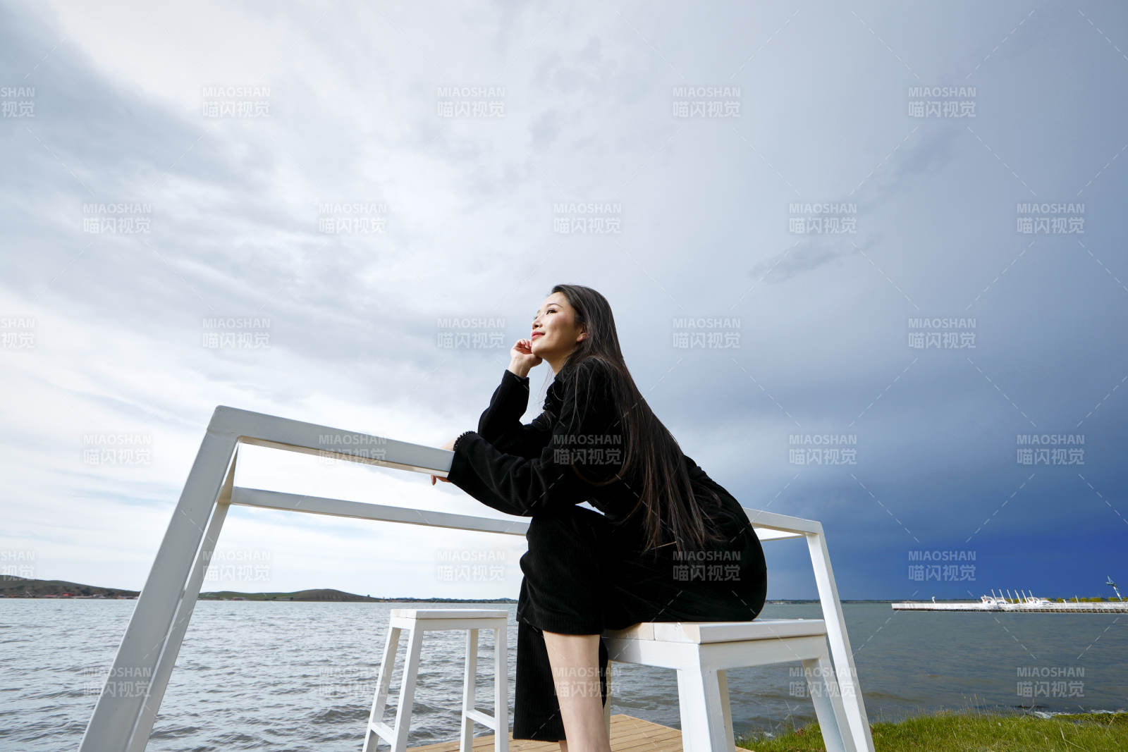 悠闲的坐在美丽湖岸码头的长发少女图片