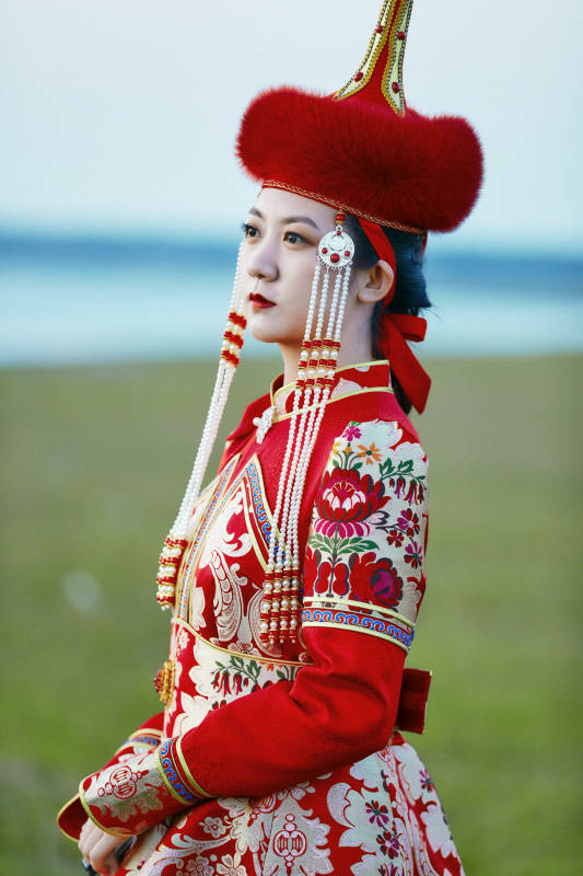 晚霞的草原湖畔穿蒙古族传统服饰的年轻女性图片