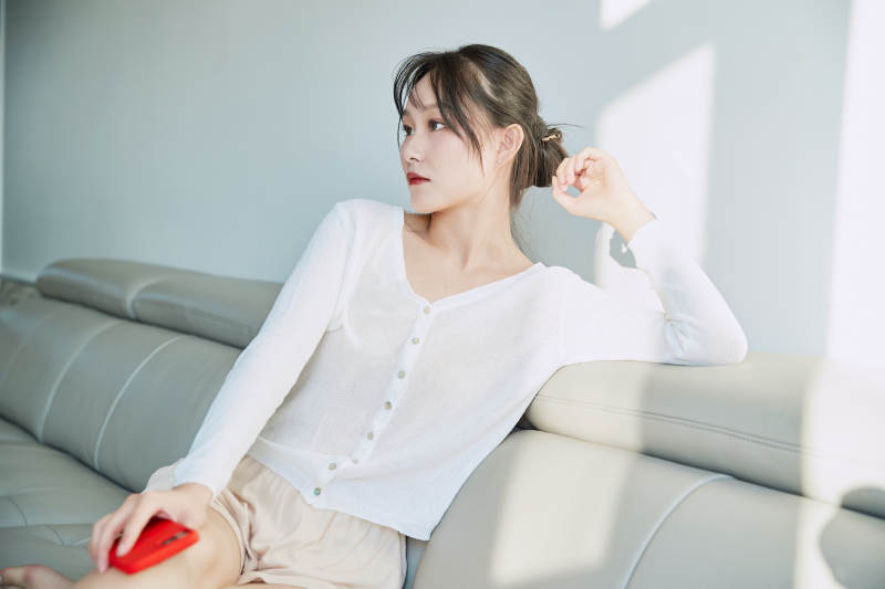 在沙发床上玩手机的年轻亚洲女性图片