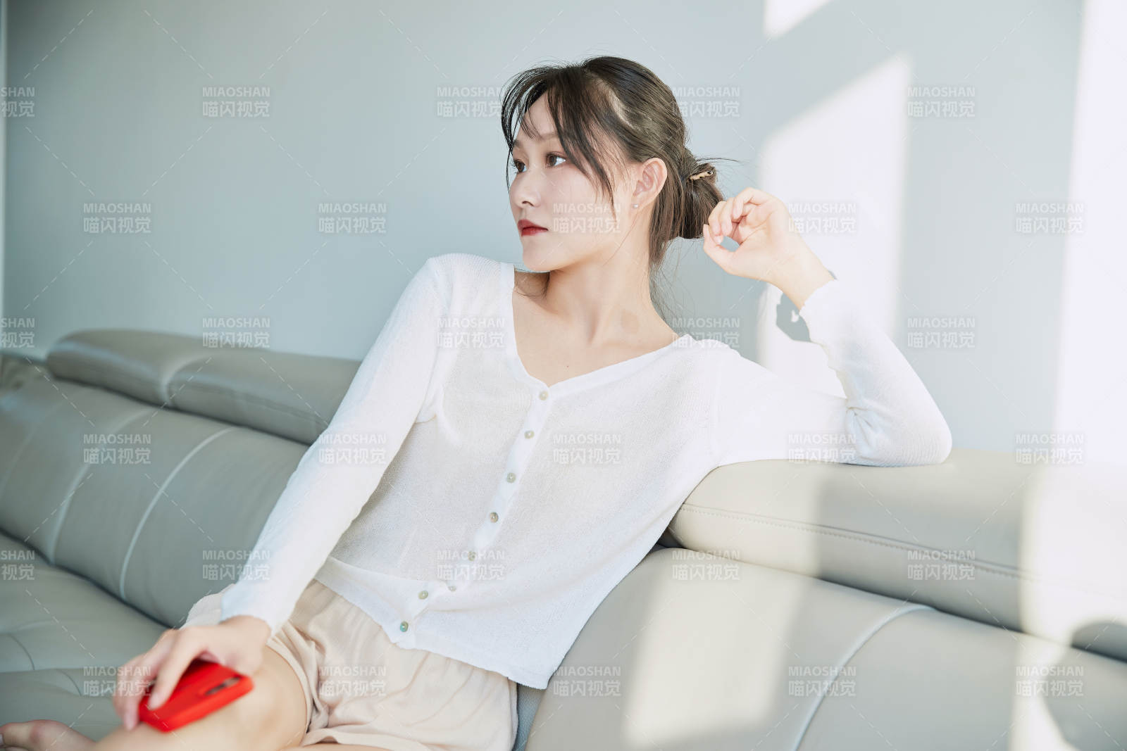 在沙发床上玩手机的年轻亚洲女性图片