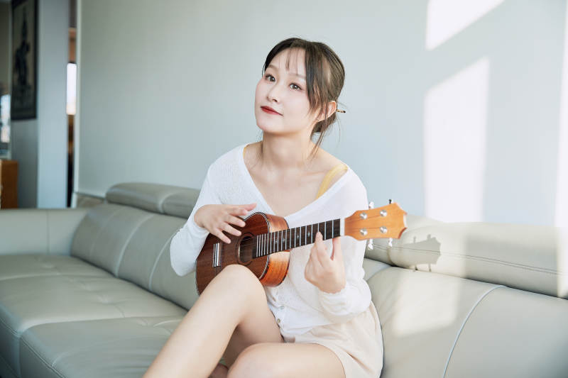 坐在沙发上弹奏尤克里里的少女图片
