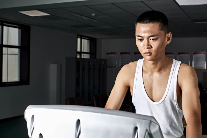 在室内用跑步机进行锻炼的亚洲健身男士形象图片