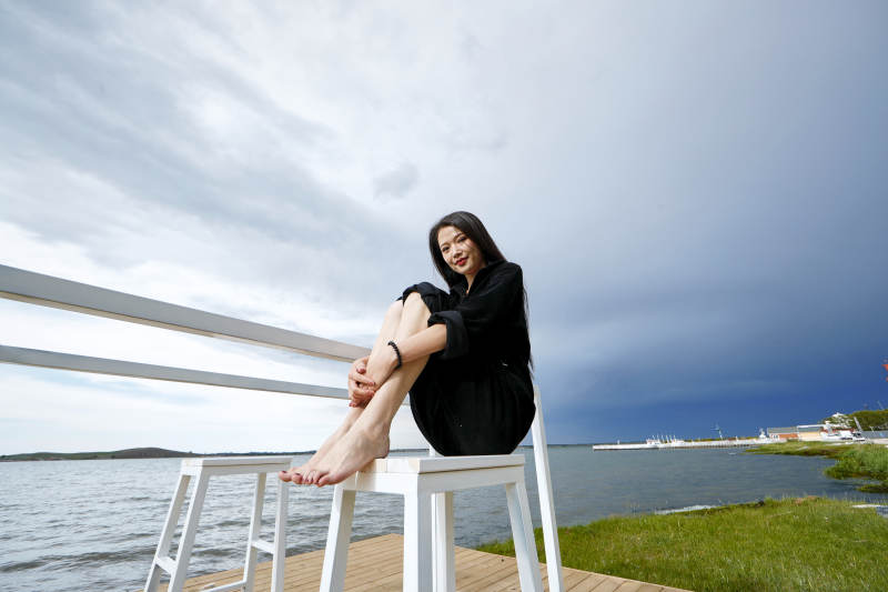 悠闲的坐在美丽湖岸码头的长发少女图片