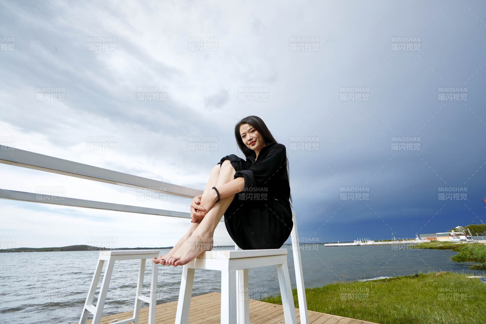 悠闲的坐在美丽湖岸码头的长发少女图片