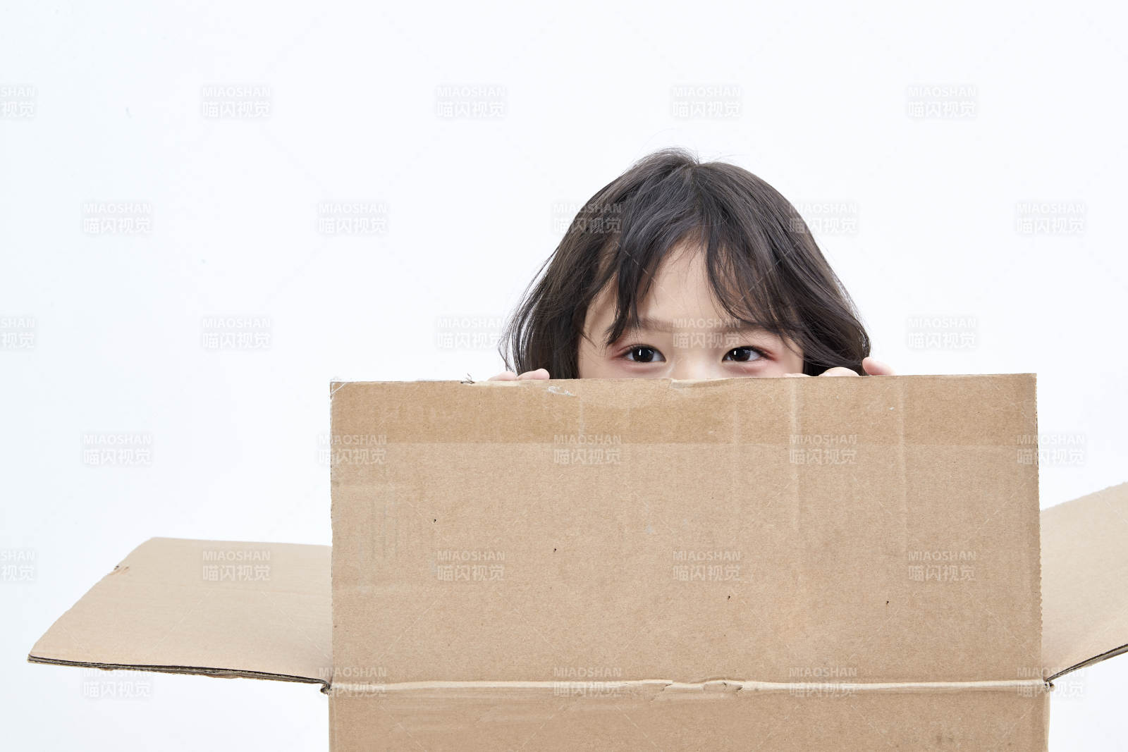 躲在纸箱中玩耍的调皮可爱亚洲小女孩儿童图片