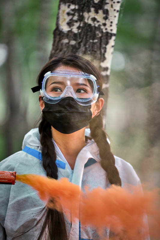 手执彩烟身穿防护服装的女性医疗人员图片