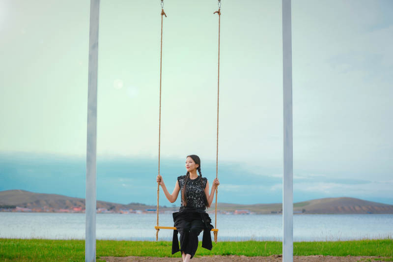 草原湖畔夕阳下荡秋千的亚洲少女图片