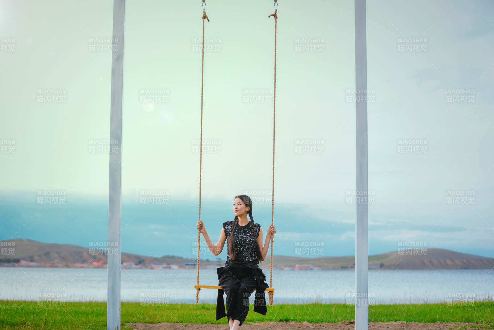 草原湖畔夕阳下荡秋千的亚洲少女图片
